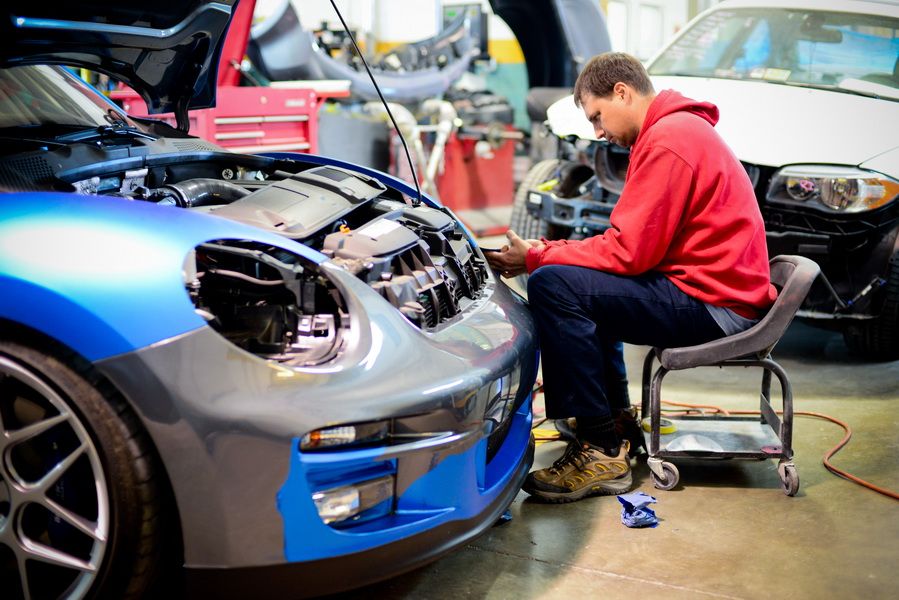 Technician Working On Blue Car With Open Hood | D&V Autobody