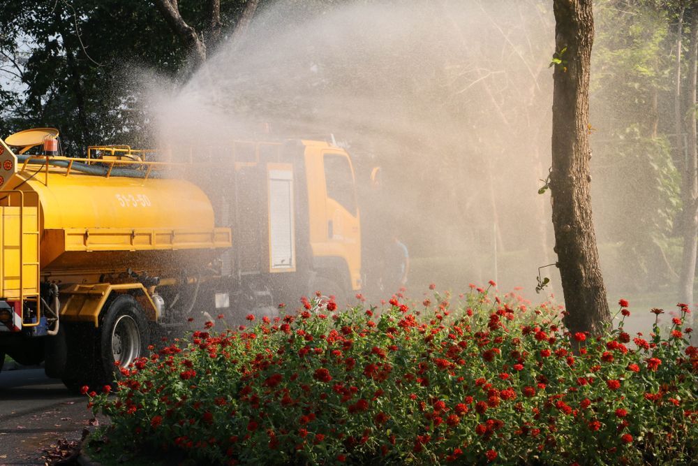 Yellow Street-sprayer Truck Misting Water Over Red Flowers — Allquip Rentals Pty Ltd in Cooroy, QLD