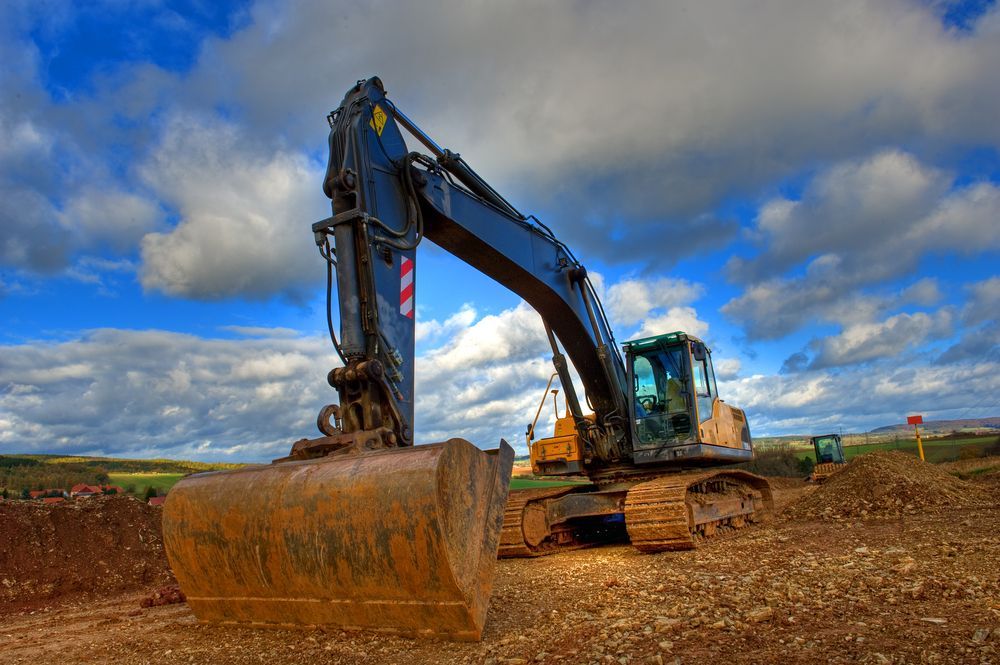 An Excavator on a Construction Site With a Cloudy Blue Sky — Allquip Rentals Pty Ltd in Cooroy, QLD