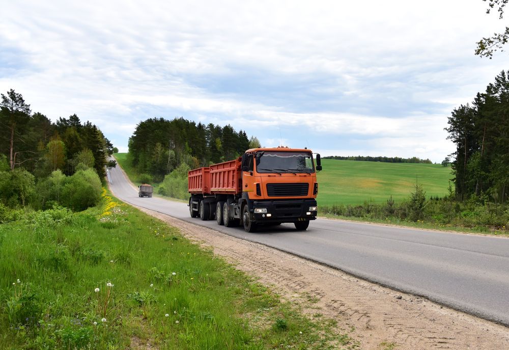 Orange Dump Truck Driving on a Paved Road — Allquip Rentals Pty Ltd in Cooroy, QLD