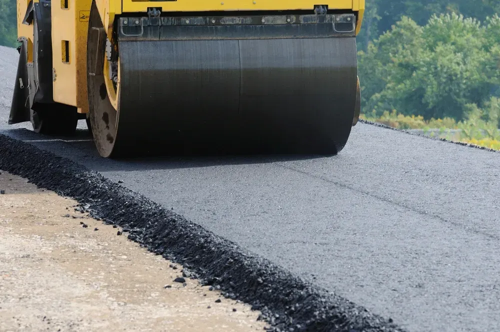Yellow road roller compacting fresh asphalt on a new road. — Allquip Rentals Pty Ltd in Cooroy, QLD