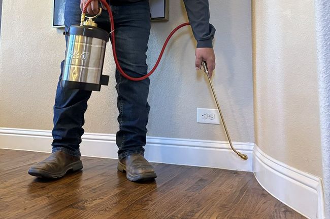 A man is spraying a wall with a sprayer.