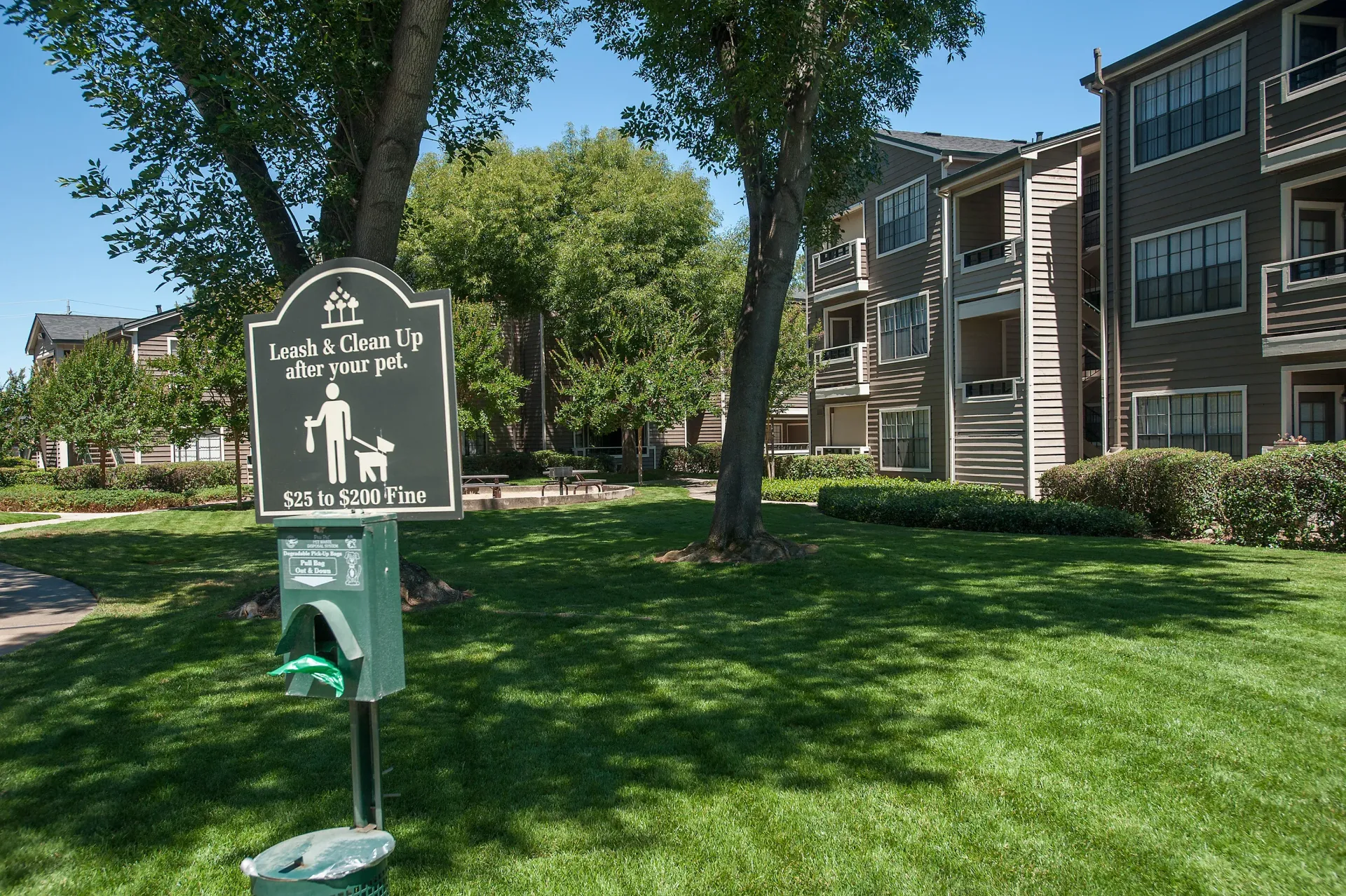 Apartment community courtyard with a pet leash-and-clean-up sign in front of a multi-unit building at The Reserve at Capital Center.