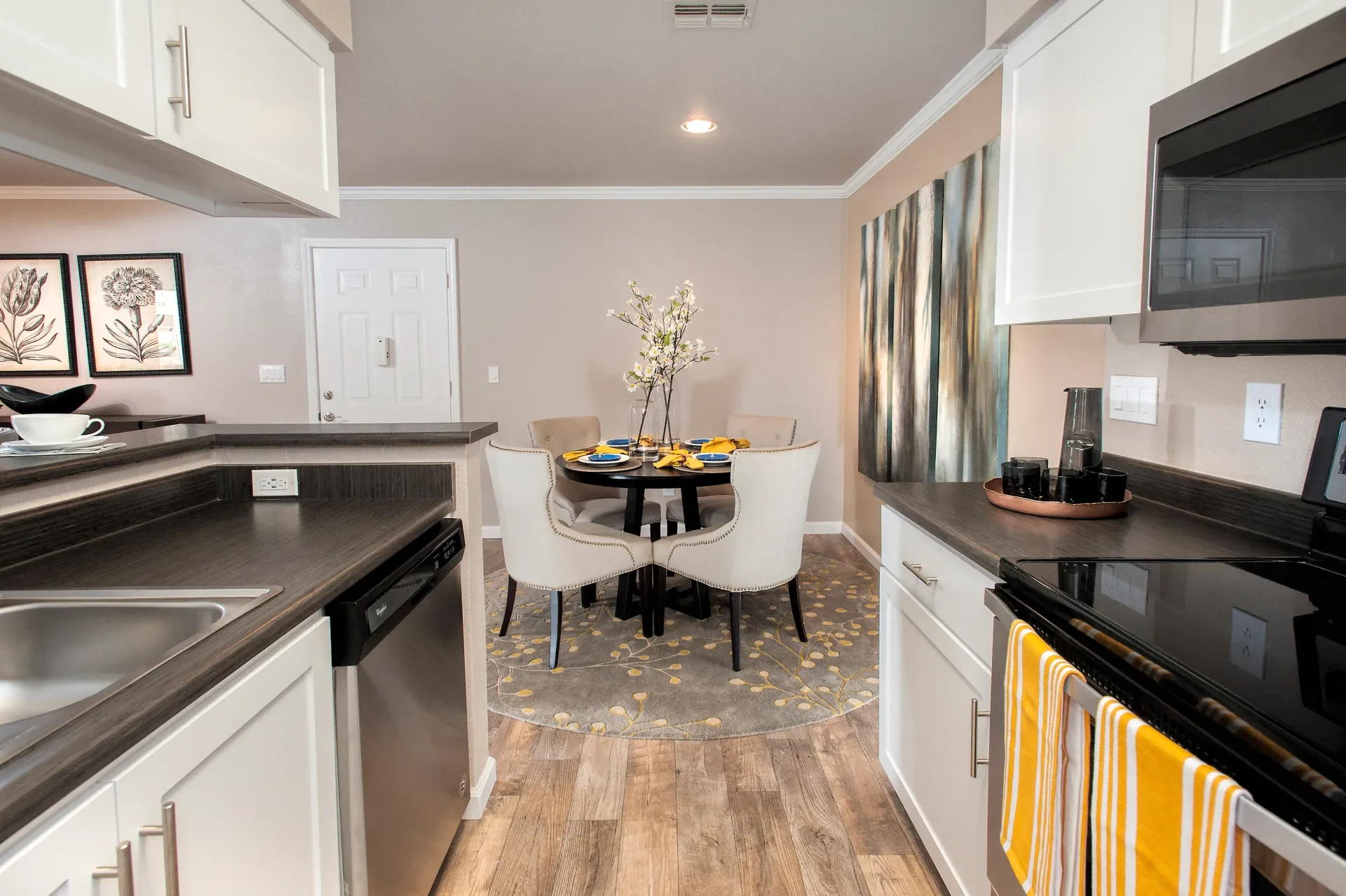 Open kitchen with white cabinets, dark countertops, stainless appliances, and a round dining table  at The Reserve at Capital Center.