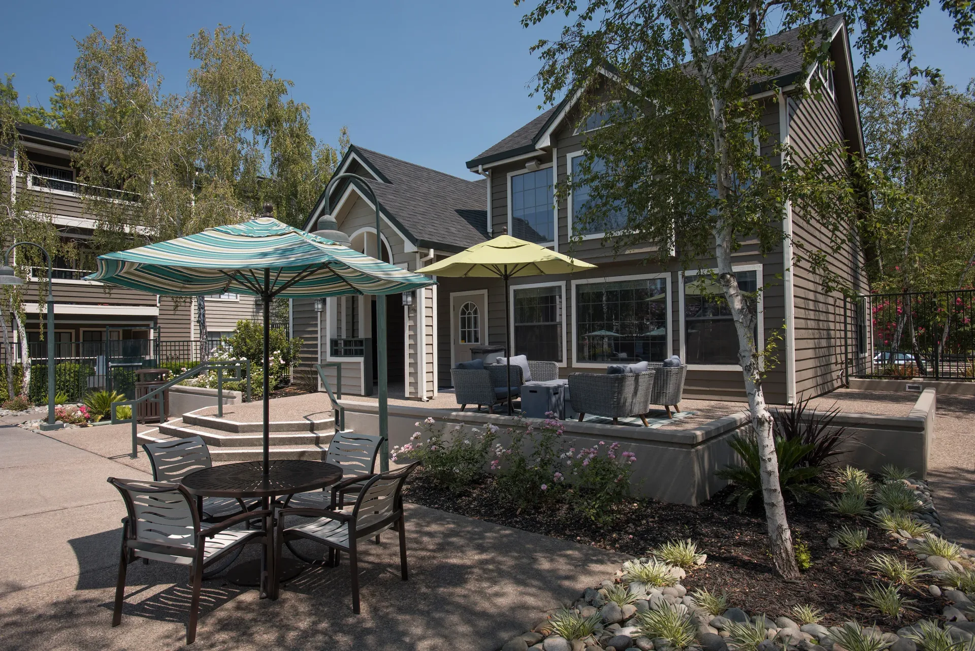Exterior communal courtyard with patio furniture and umbrellas near an apartment building at The Reserve at Capital Center.