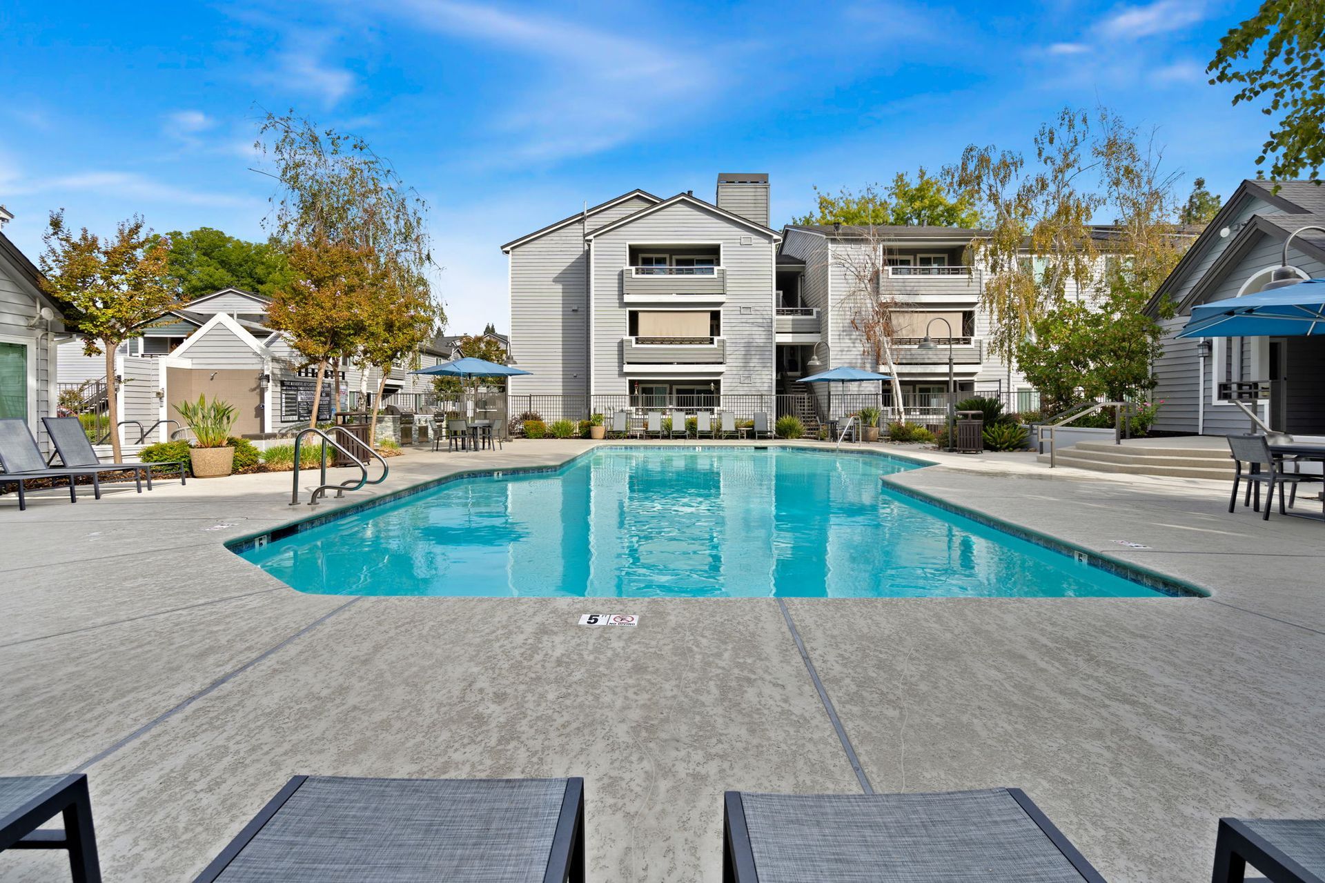 Outdoor community pool with lounge chairs and apartment buildings in the background at The Reserve at Capital Center.
