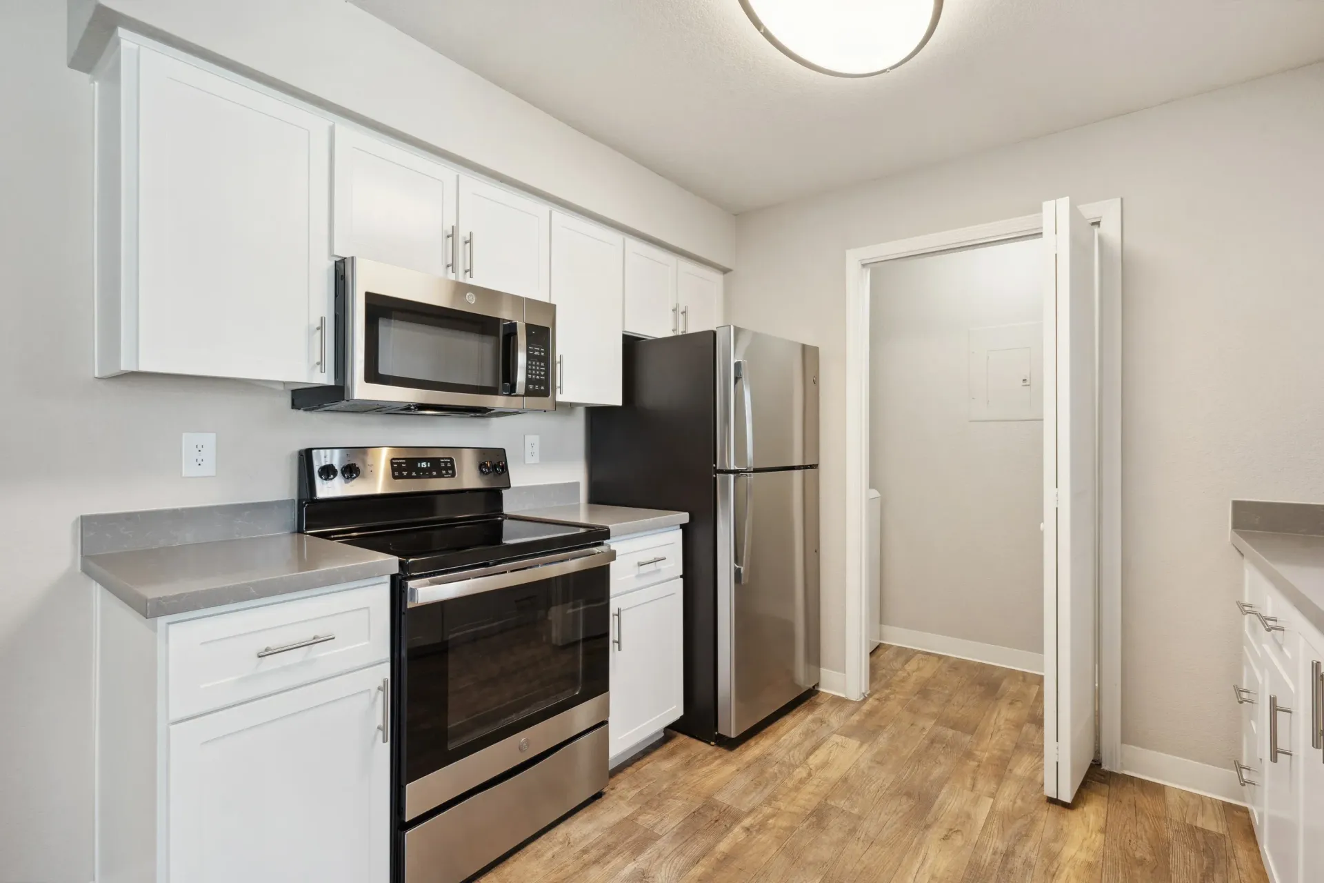 Modern apartment kitchen with white cabinets, stainless-steel appliances, and wood-look flooring at The Reserve at Capital Center.