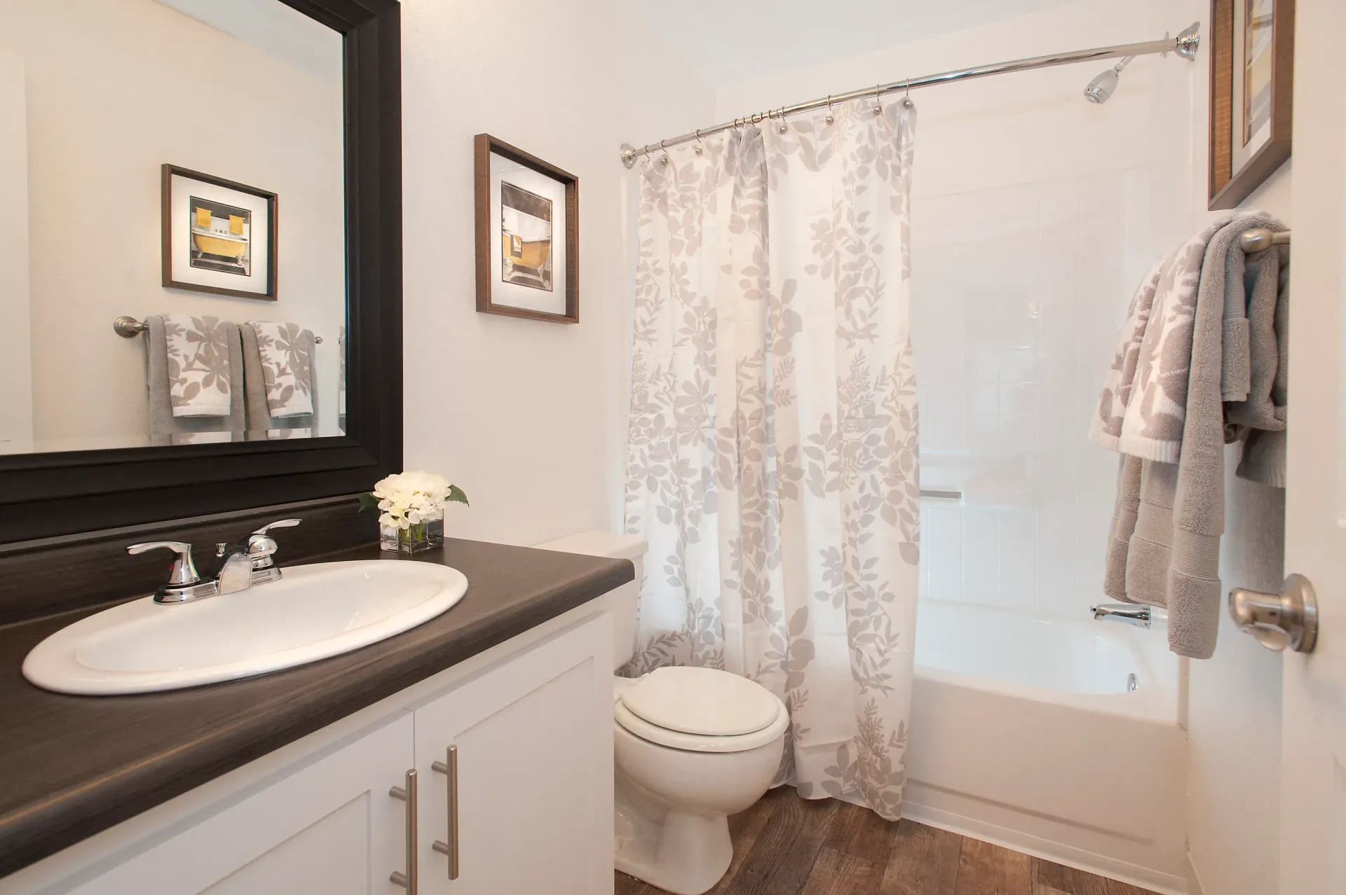 Bathroom with vanity sink, large mirror, toilet, and a tub/shower with patterned curtain at The Reserve at Capital Center.