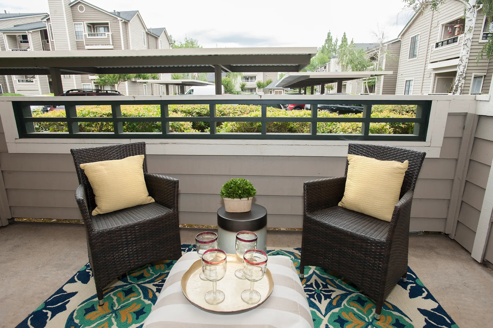 Balcony seating area with two wicker chairs and a small table in a residential community at The Reserve at Capital Center.