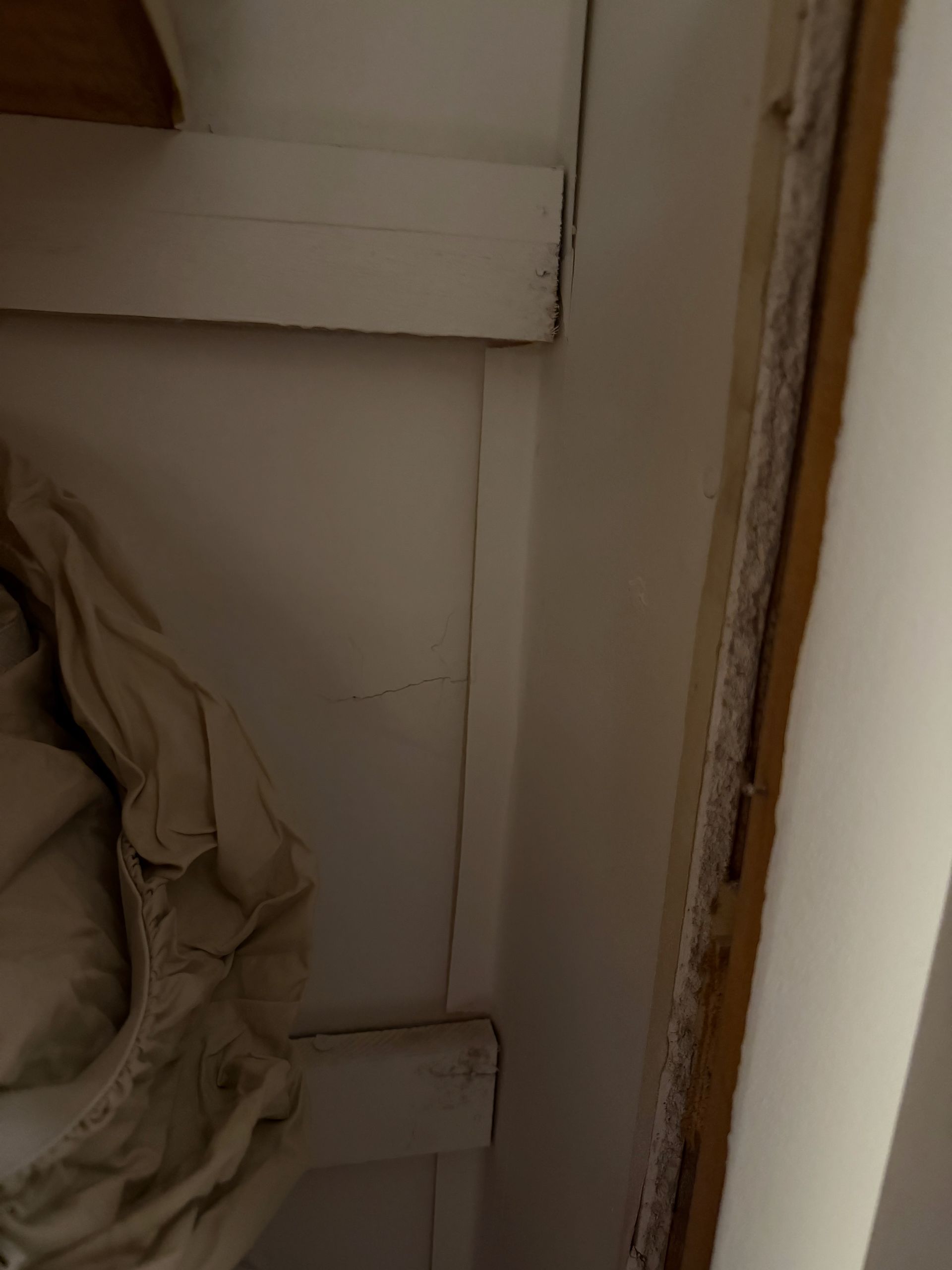 Close-up of a beige fabric item hanging inside a white cabinet or closet.