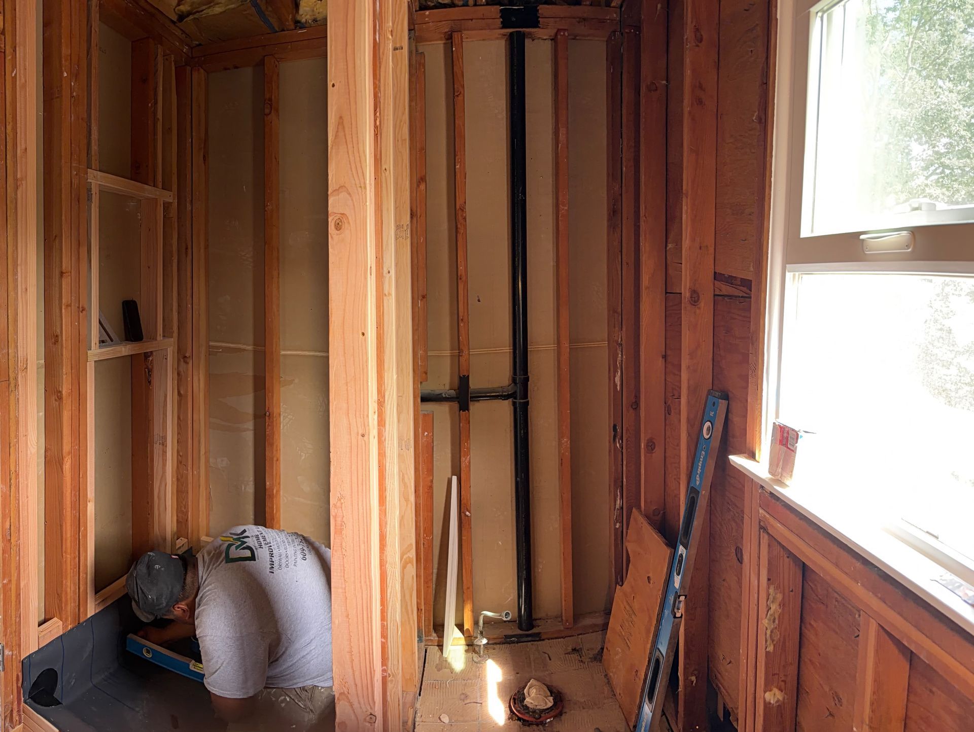 Unfinished wooden room with exposed studs, a window, and construction tools on the floor.
