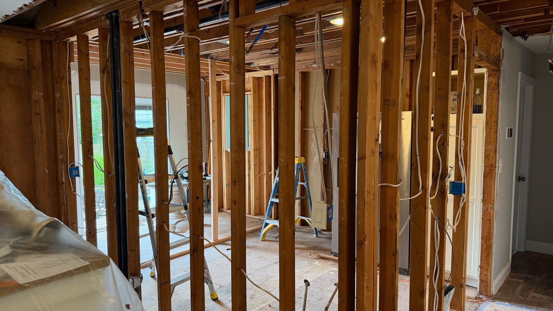 Interior under renovation with exposed wooden studs and construction debris on the floor.