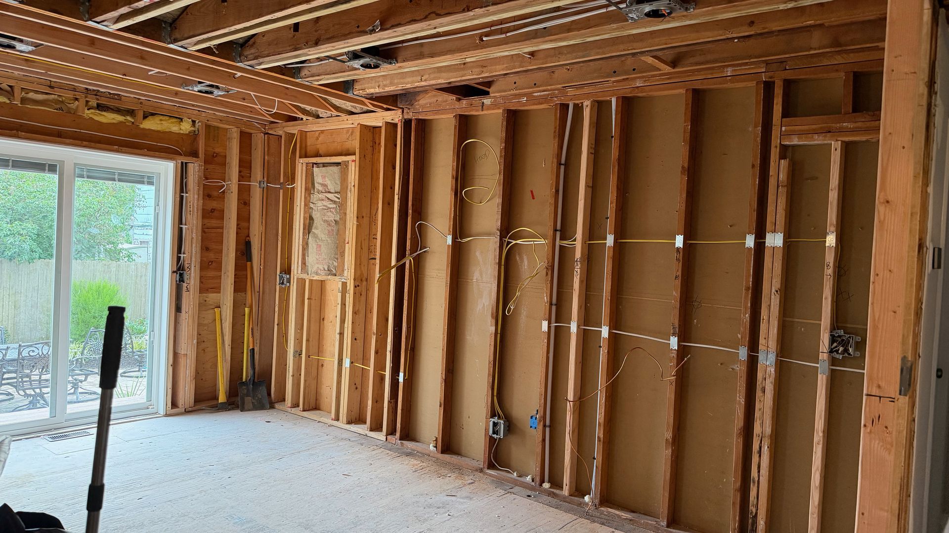Interior of a house under construction, with exposed wooden framing and a partially finished room.
