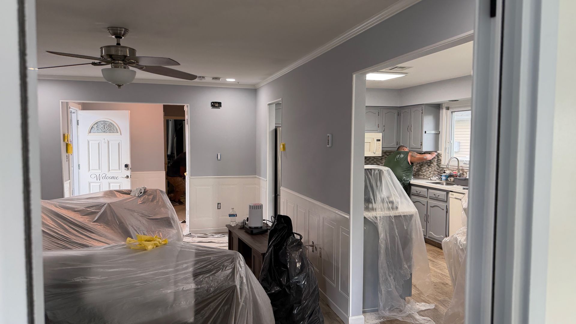 Living room and hallway with furniture wrapped in plastic during home renovation
