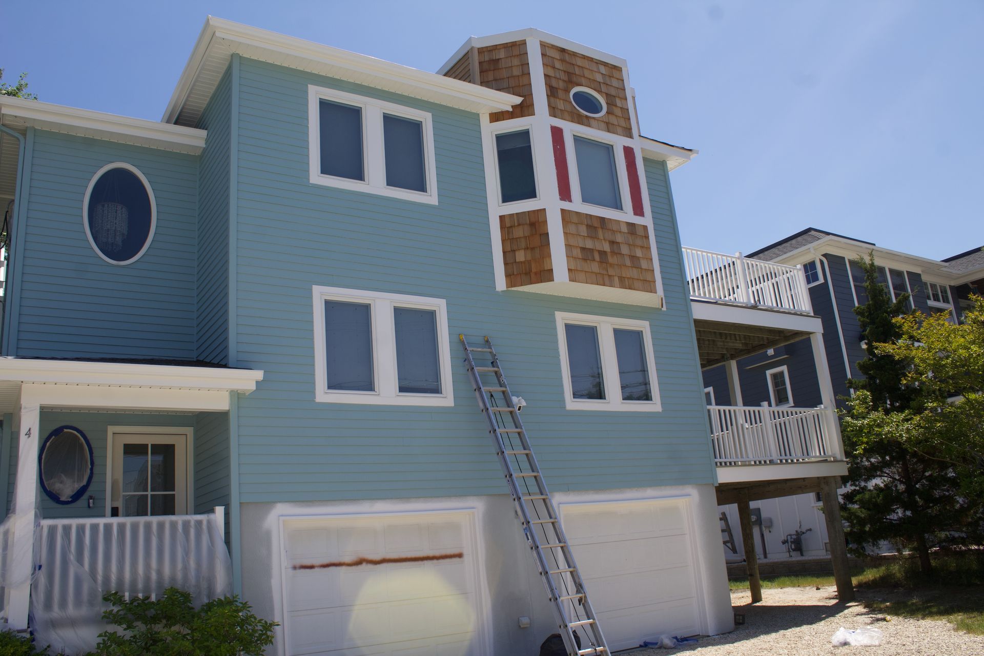 Blue beach house exterior with white trim and a ladder leaning against the front wall