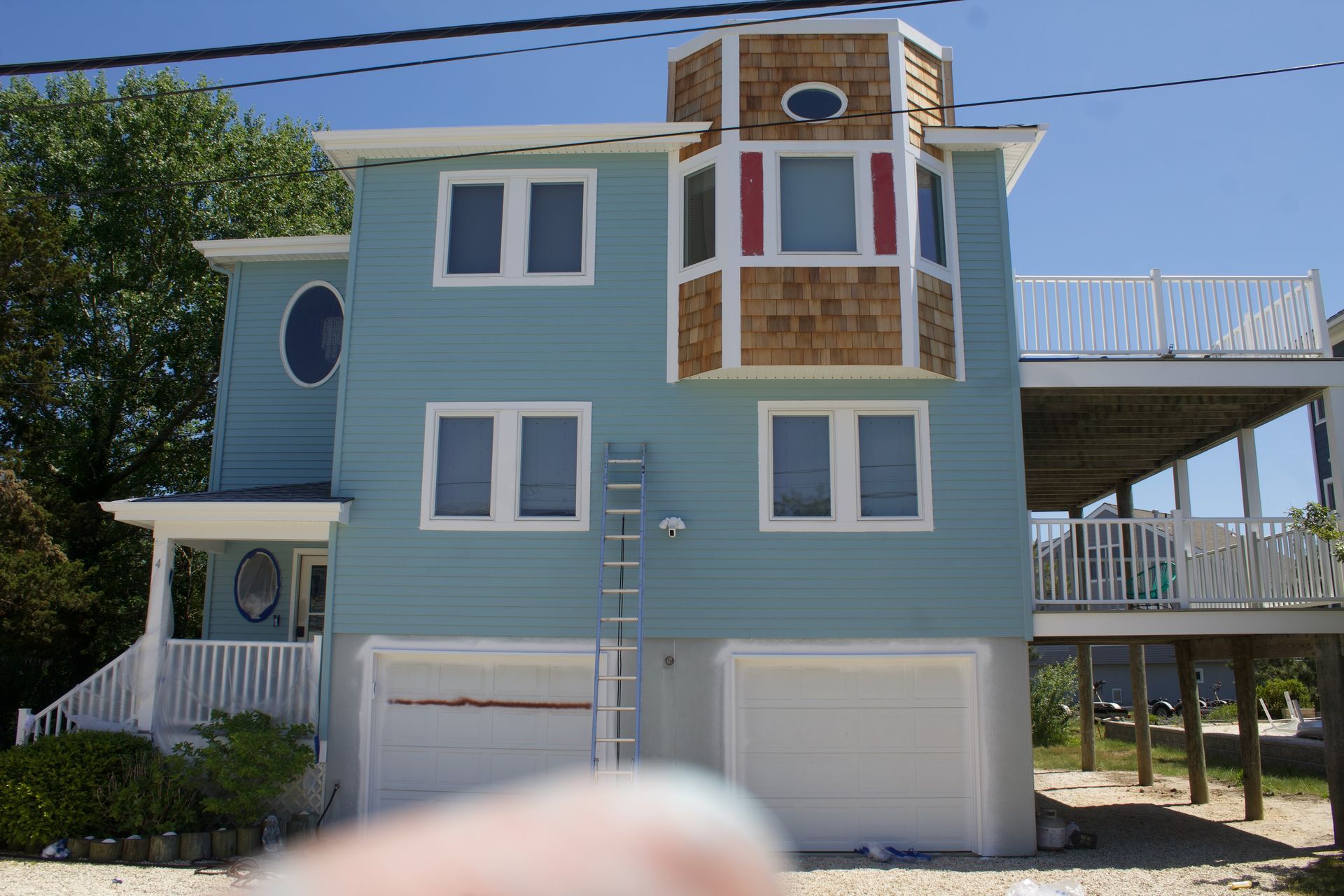 Blue beach house with white trim, bay windows, balconies, and garages under a clear sky