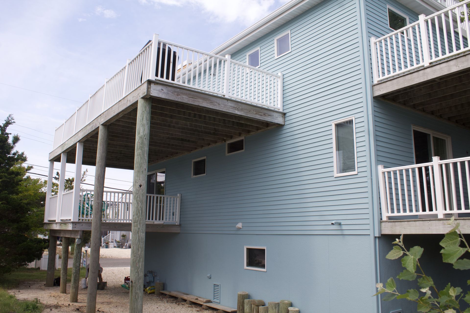 Light blue apartment building with raised decks and white railings outdoors