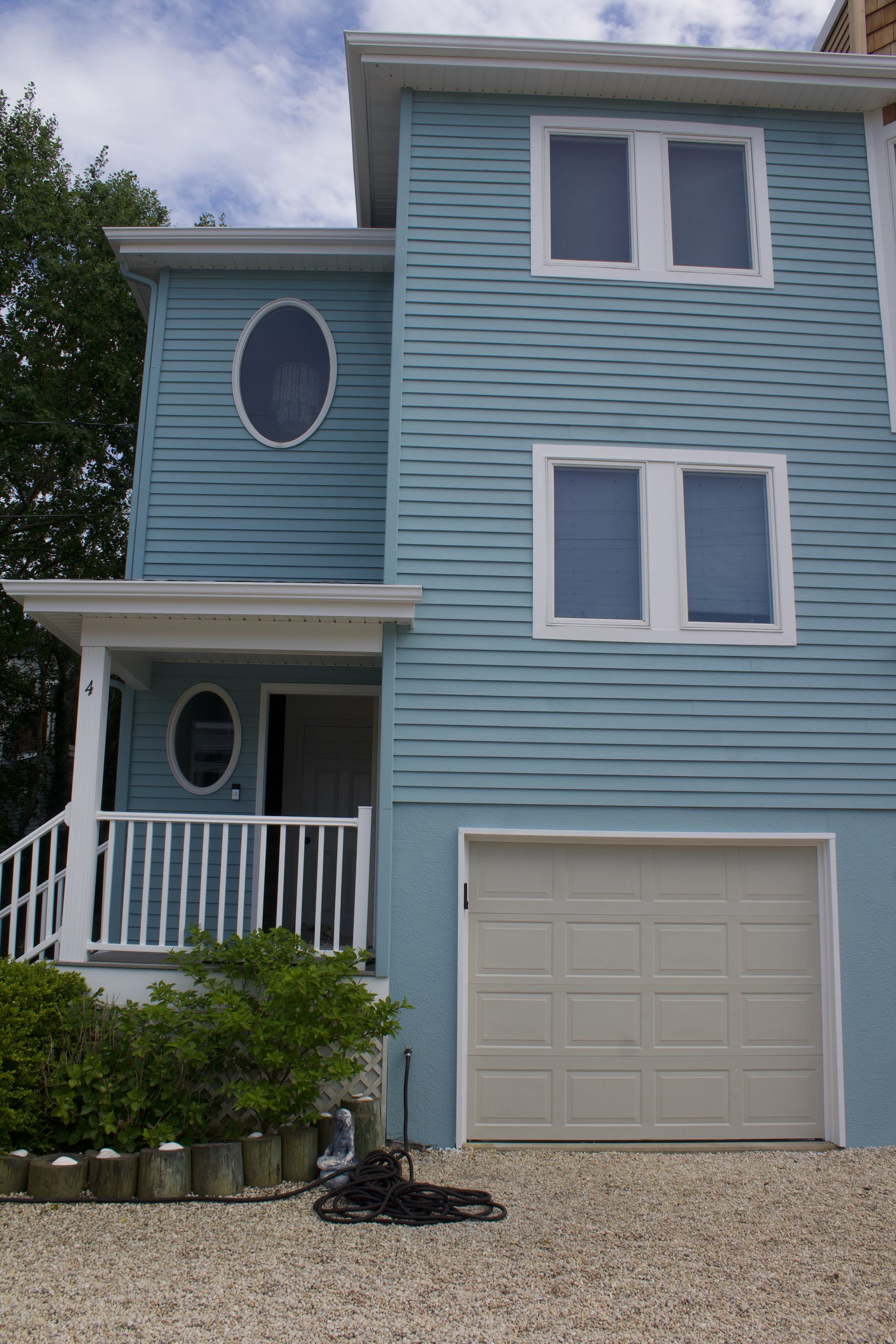 Blue two-story house with white trim, garage, and small front porch.