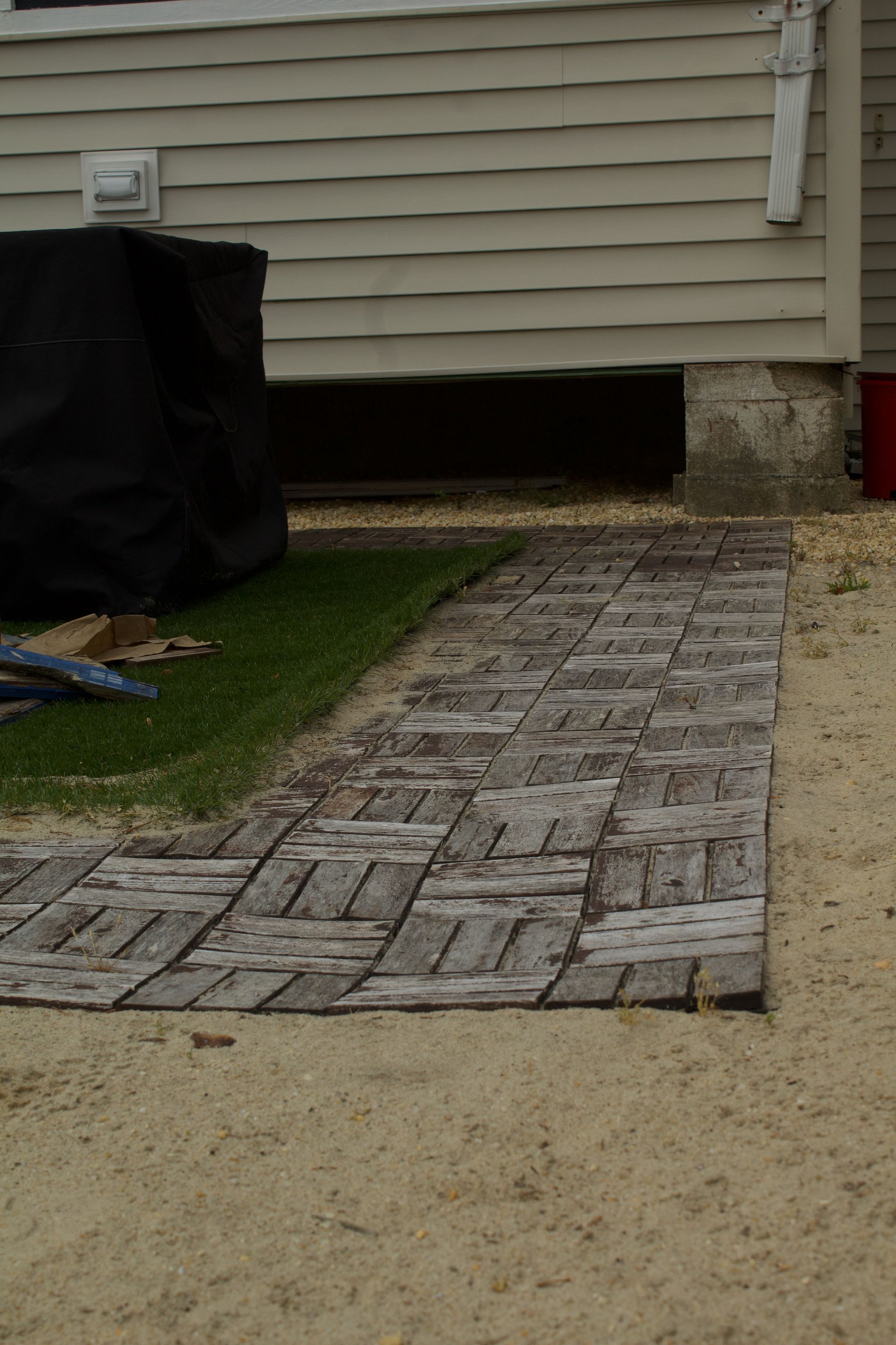 Brick walkway leading to a house entrance beside a lawn and gravel path