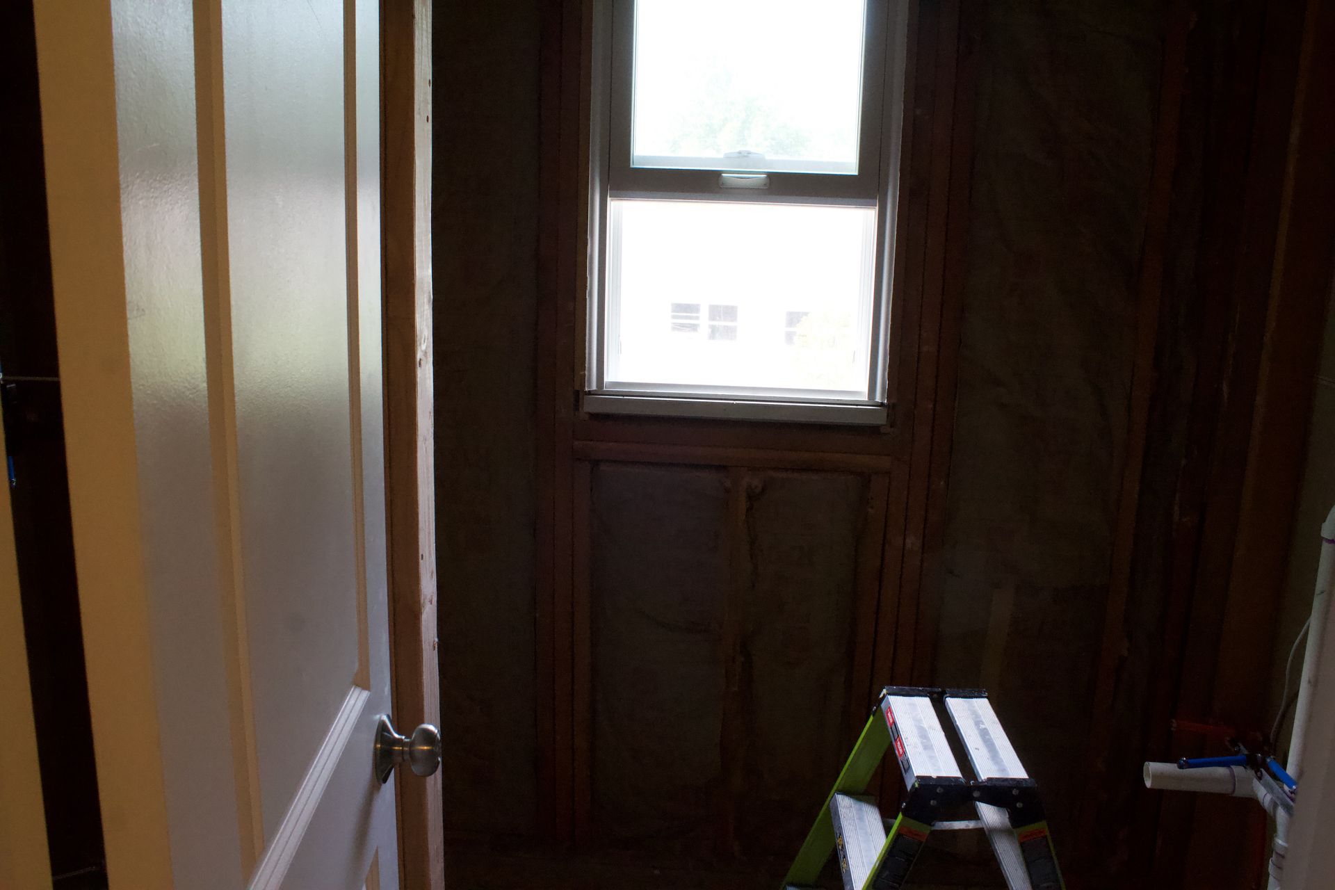 Dim hallway with an open door, window, and a small ladder near the floor.