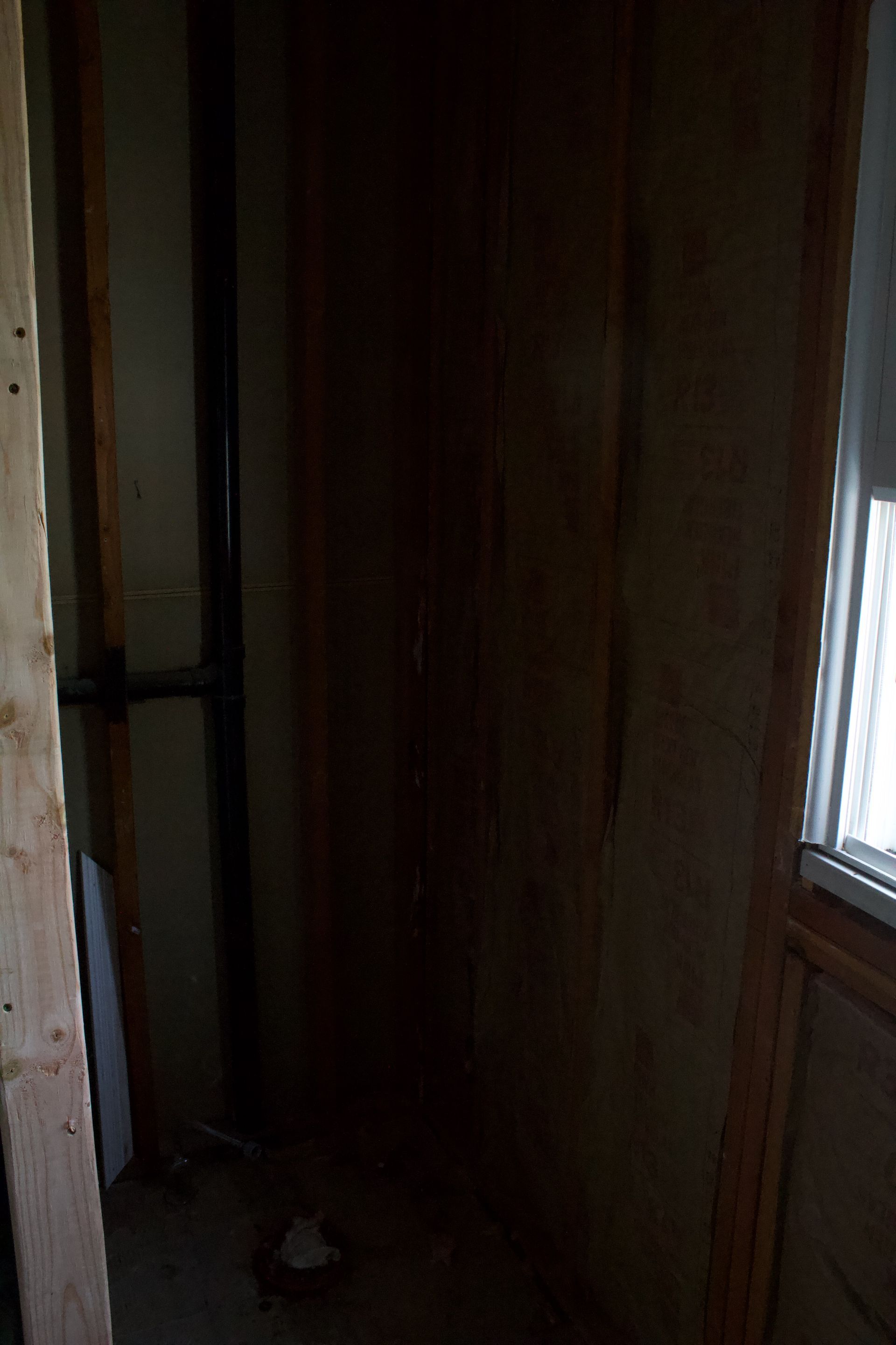 Dim narrow hallway with wood-paneled walls and a window on the right.