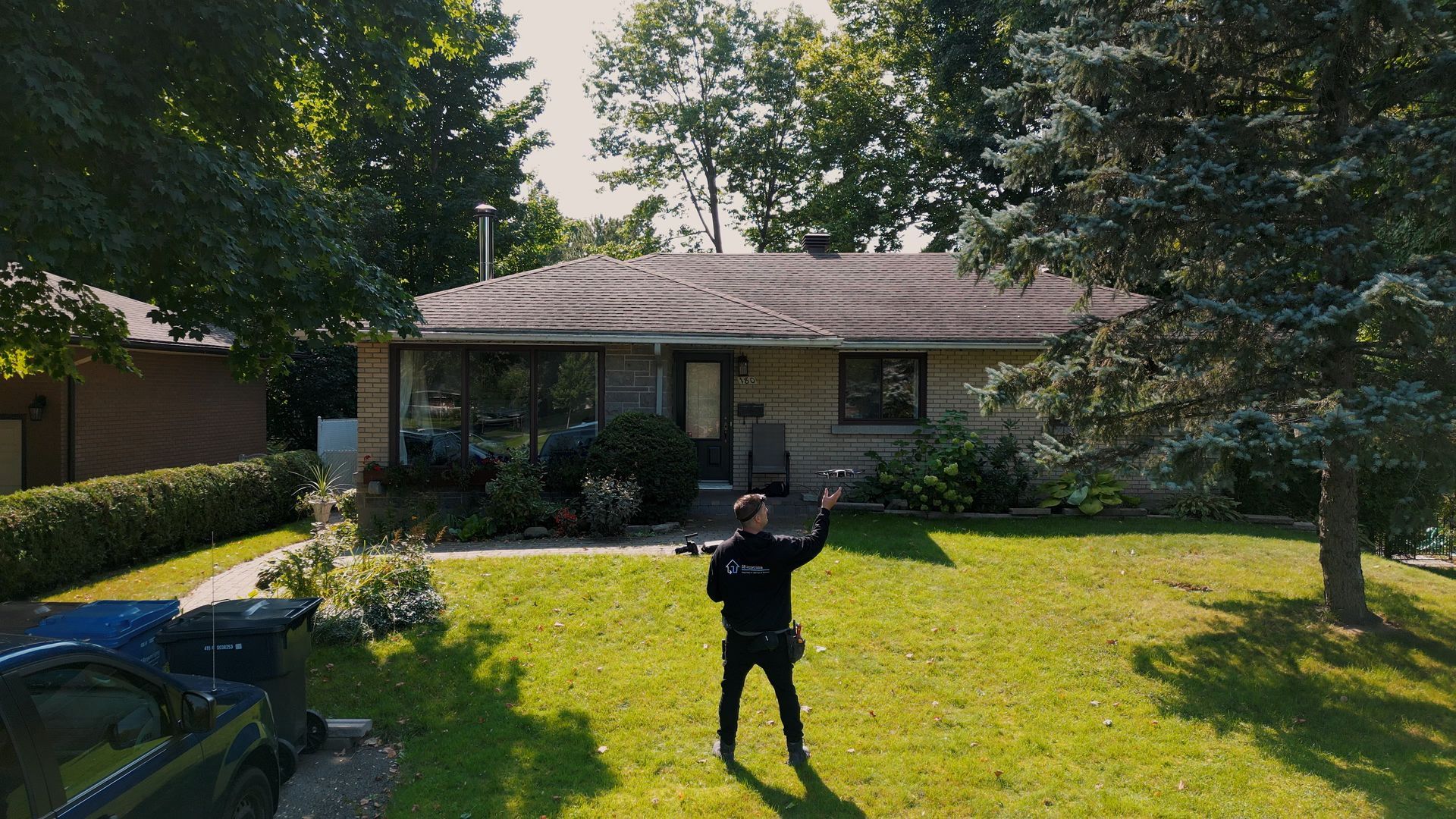 Un homme debout sur l'herbe désigne une maison de plain-pied.