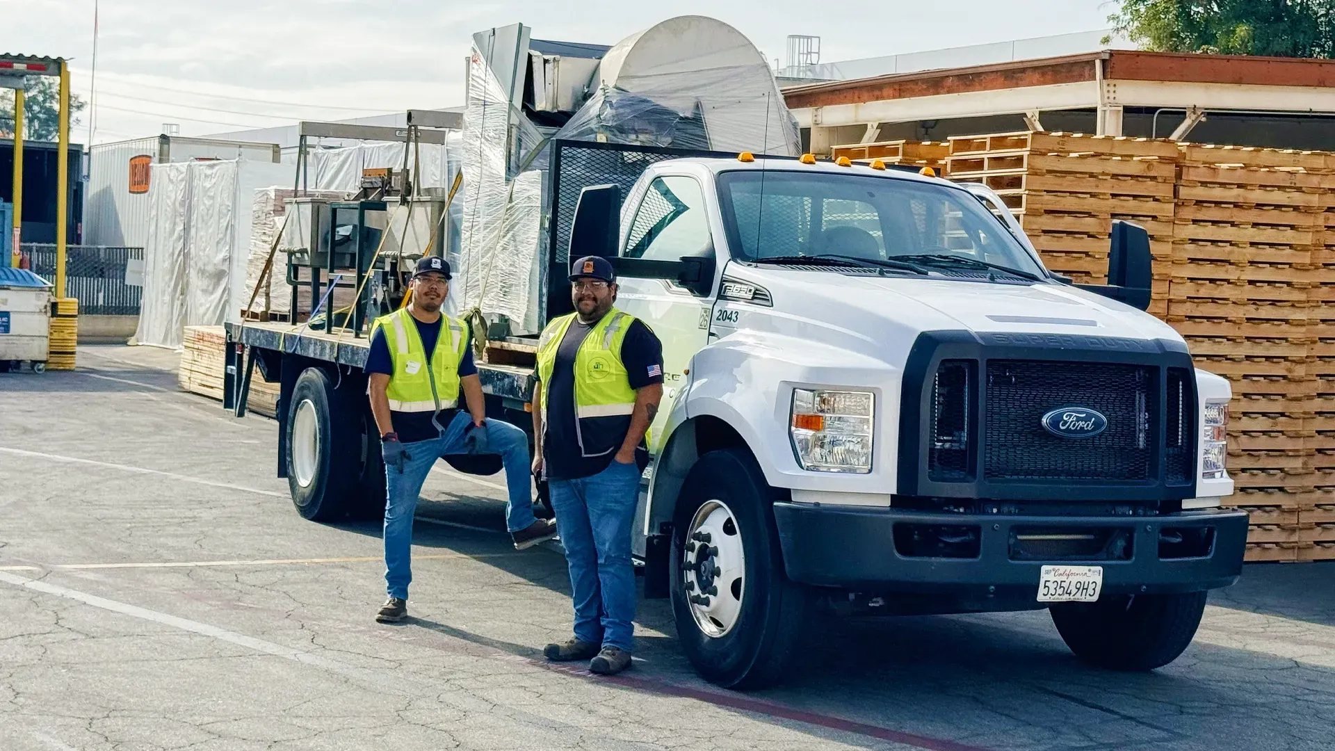 A flatbed truck delivering construction equipment to a job site in Santa Fe Springs.