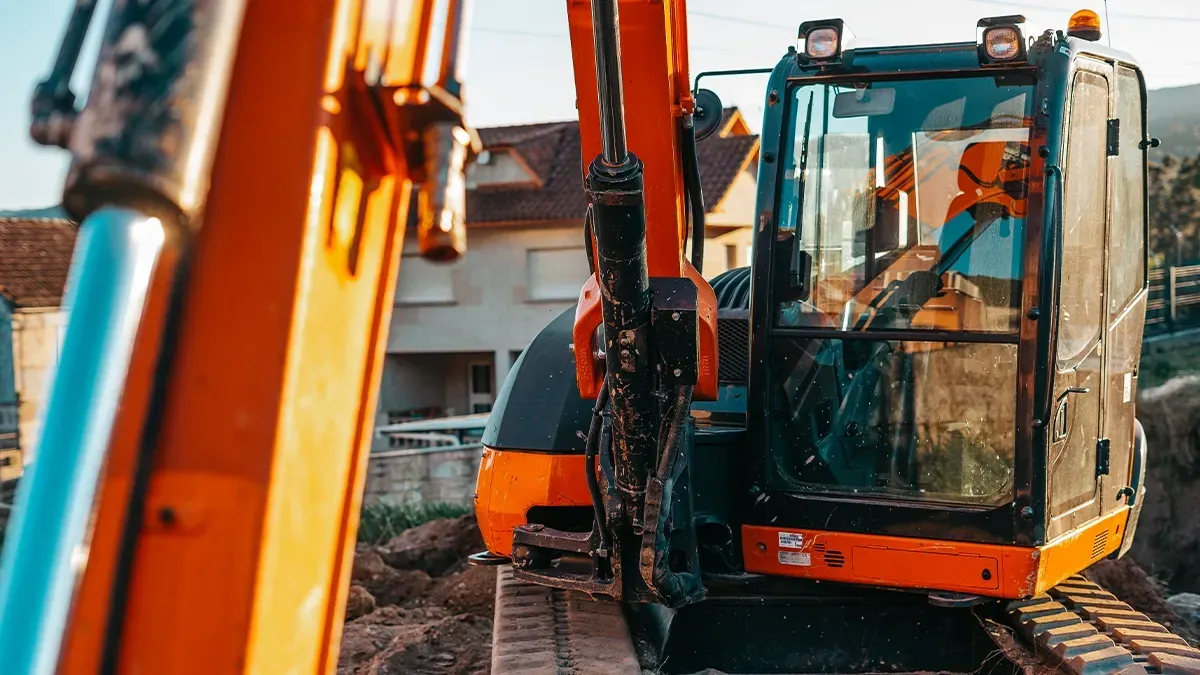 A compact mini excavator positioned on a residential job site, surrounded by dirt and construction materials, ready for excavation work.