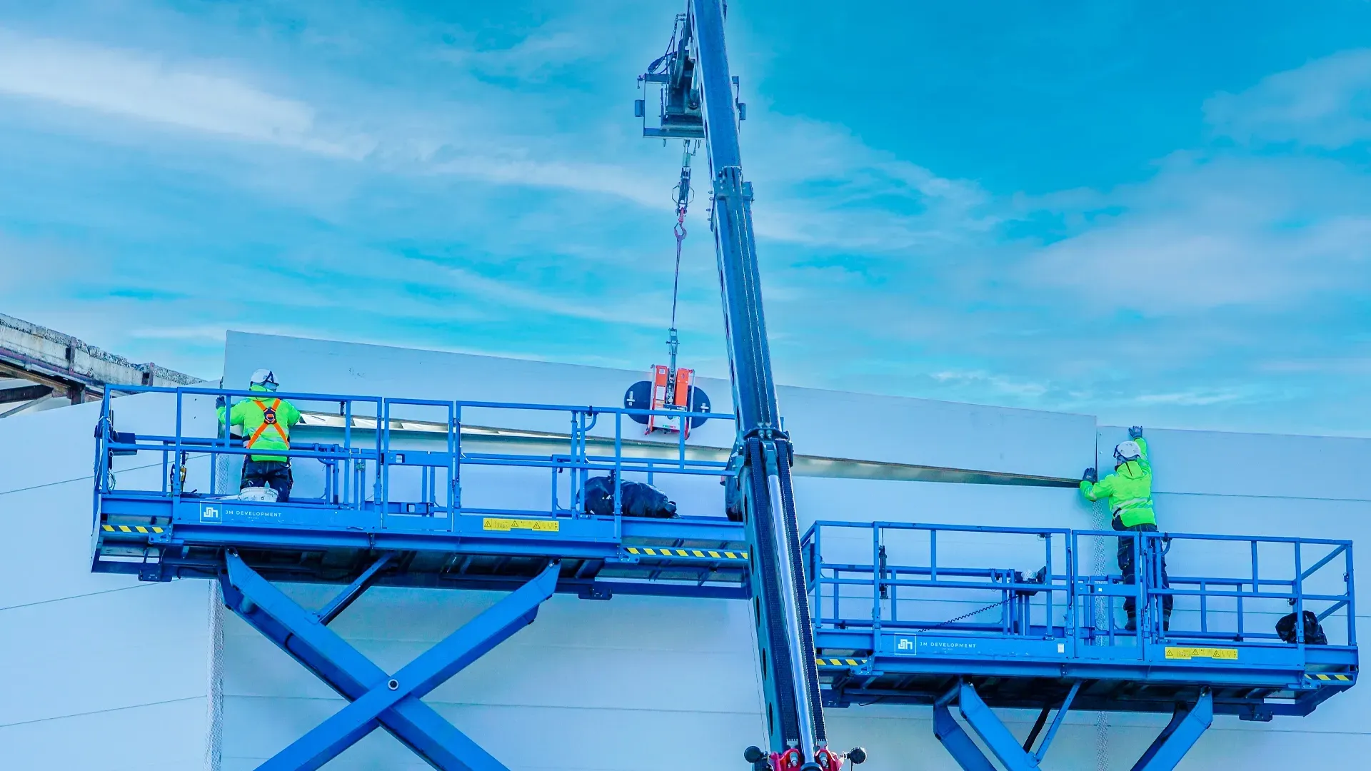 JM Development crew using scissor lifts and a crane to install materials at elevation