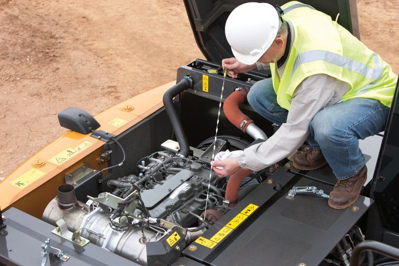 A man in a hard hat is working on the engine of a vehicle