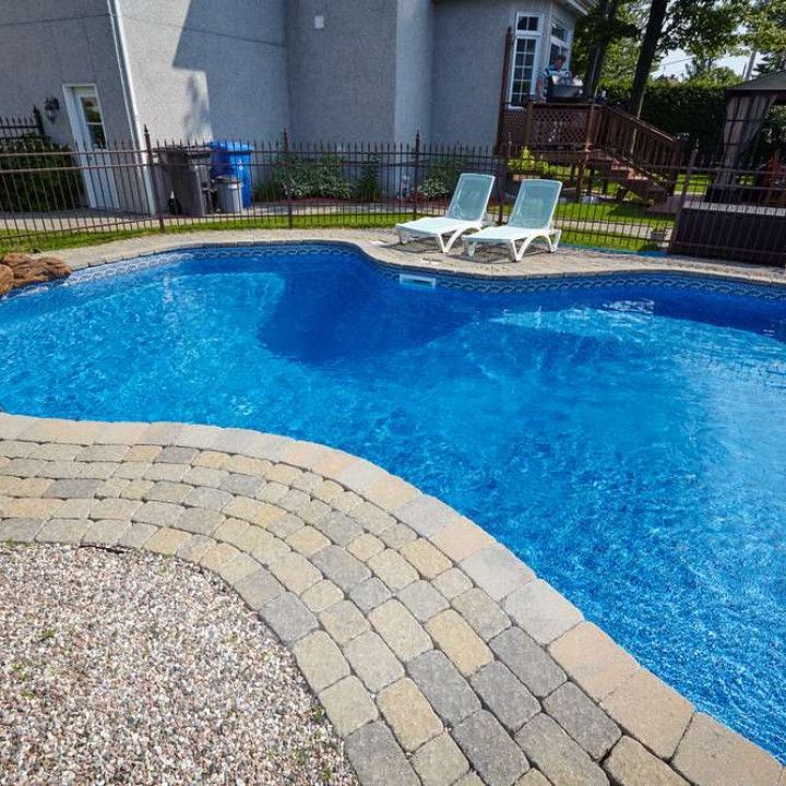 A large swimming pool with a brick walkway surrounding it
