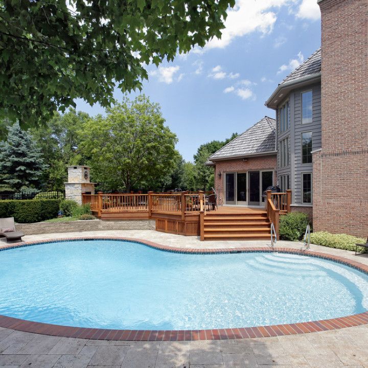 A large swimming pool in front of a brick house