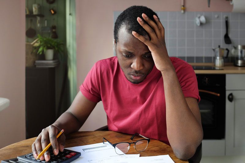 A man is sitting at a table using a calculator. A man is sitting at a table using a calculator.