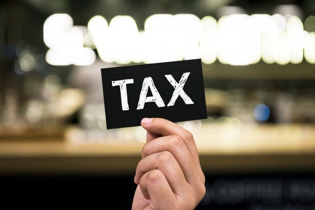 A person is holding a card with the word tax written on it. A person is holding a card with the word tax written on it.