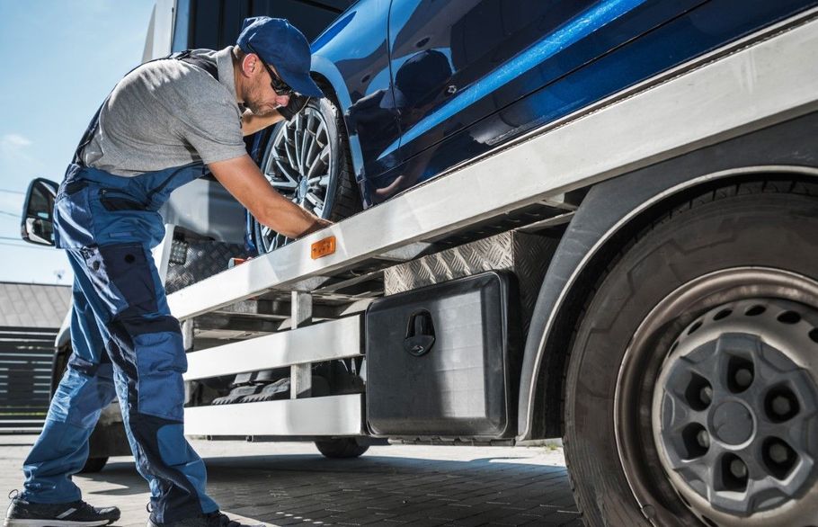 Mechanic inspecting a blue truck’s wheel and side panel outdoors