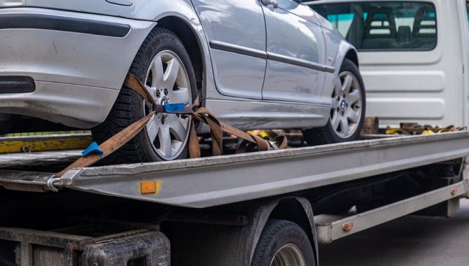 Silver car strapped on a flatbed tow truck for transport