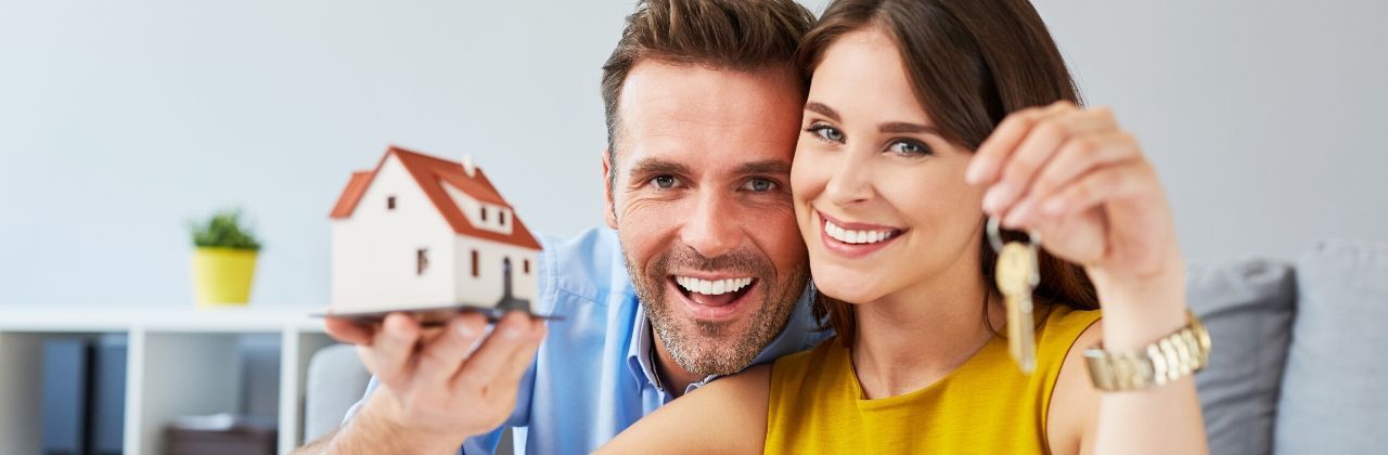 A happy couple with keys and a model home. Big Valley Mortgage, your trusted mortgage company for smooth home financing.