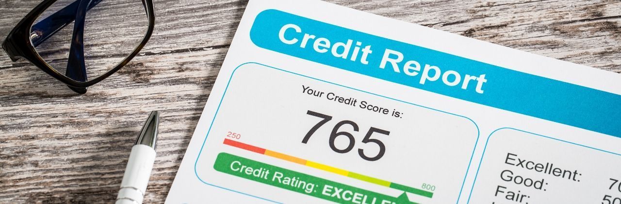 
A credit report on a wooden desk showing a score of 765 with the rating 