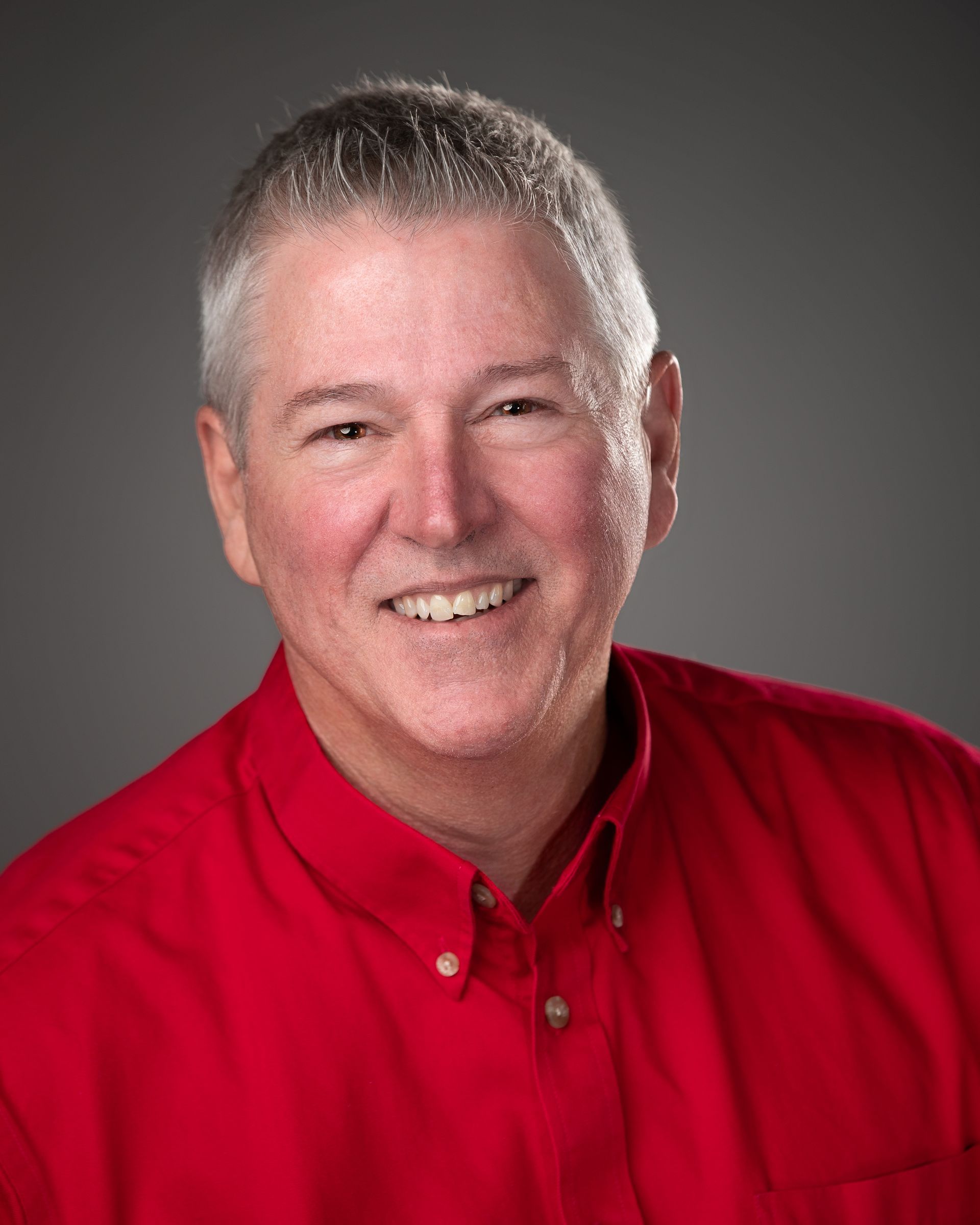 Jeff Silver smiling in a red button-up shirt against a gray studio backdrop | Mortgage Lender in Roseville, CA