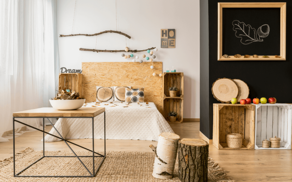 A rustic bedroom with a wood-chip headboard, natural decor accents, wooden crate storage, and a black wall with art.