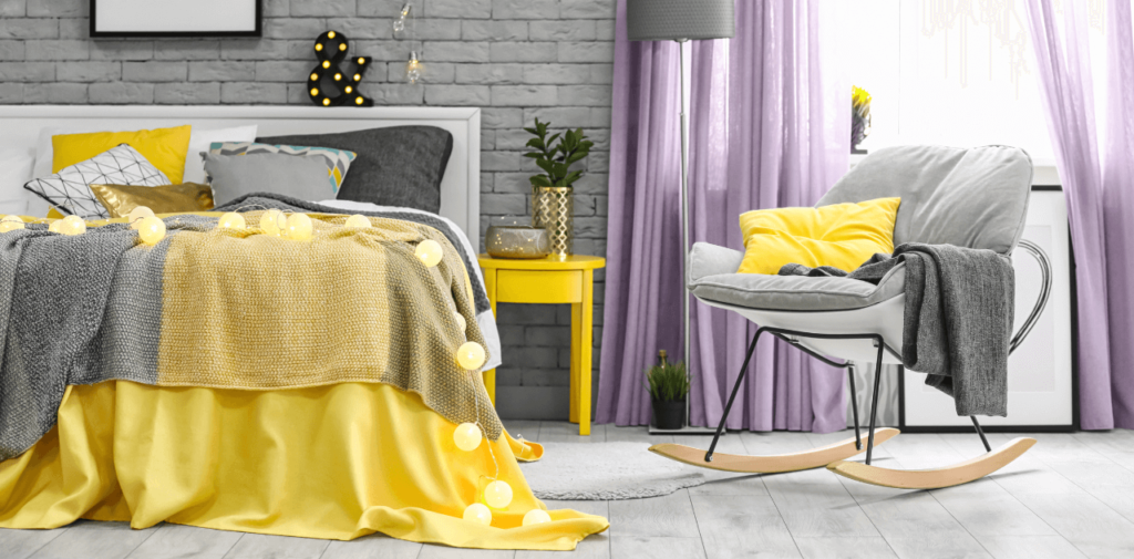 A bedroom with a bed, chair, nightstand, and purple curtains.