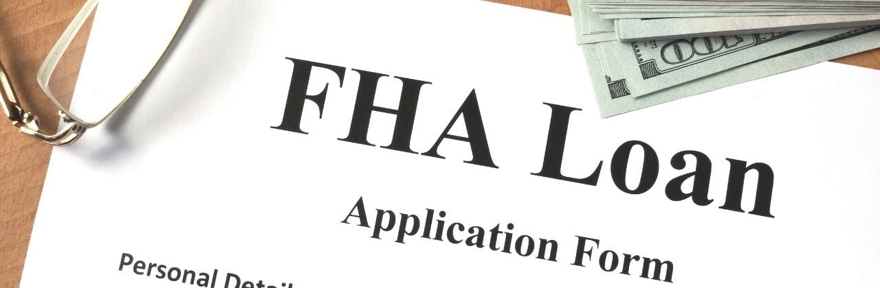 FHA Loan application form on a desk with a stack of cash and eyeglasses.