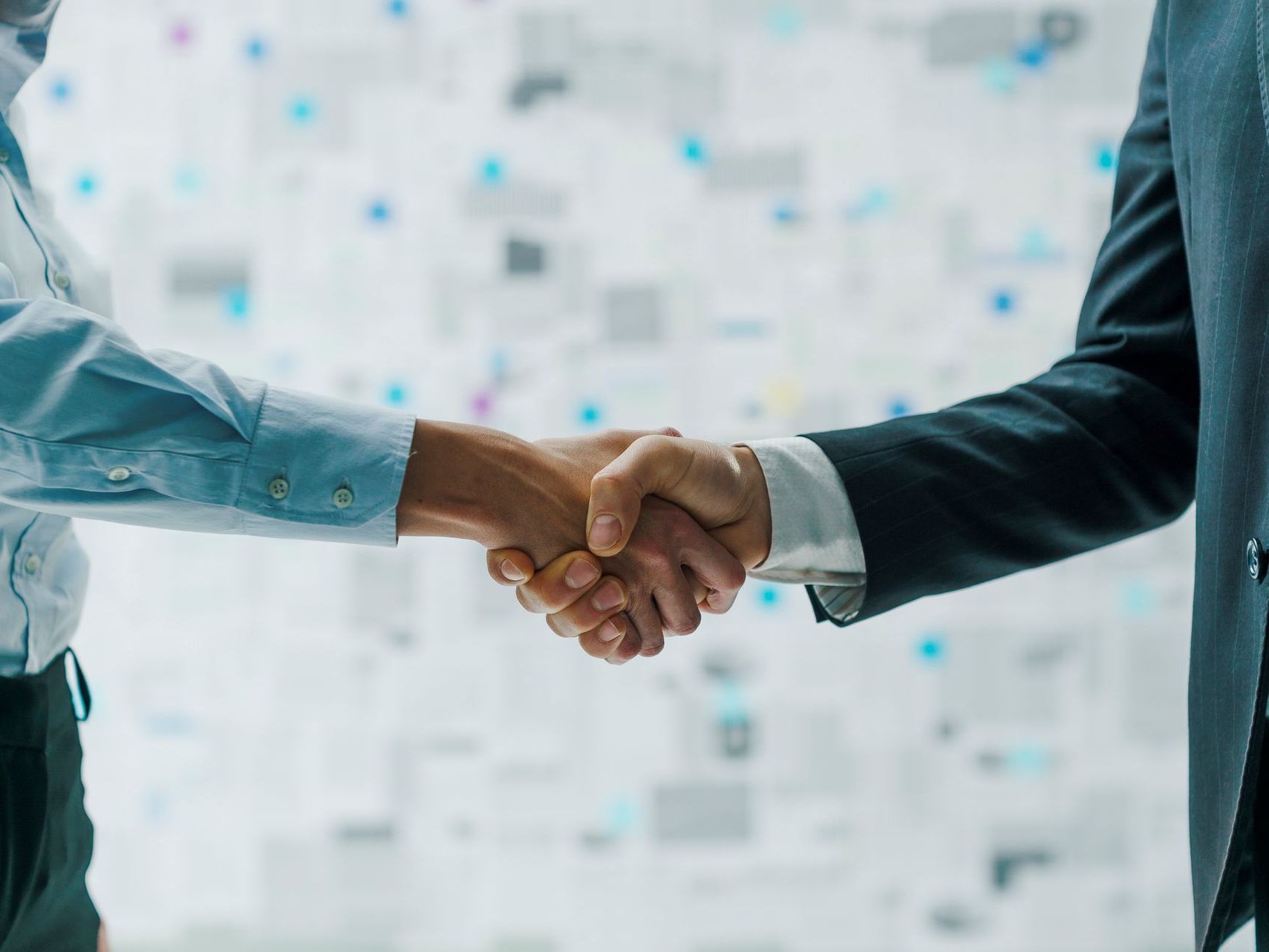 A man and a woman are shaking hands in an office.