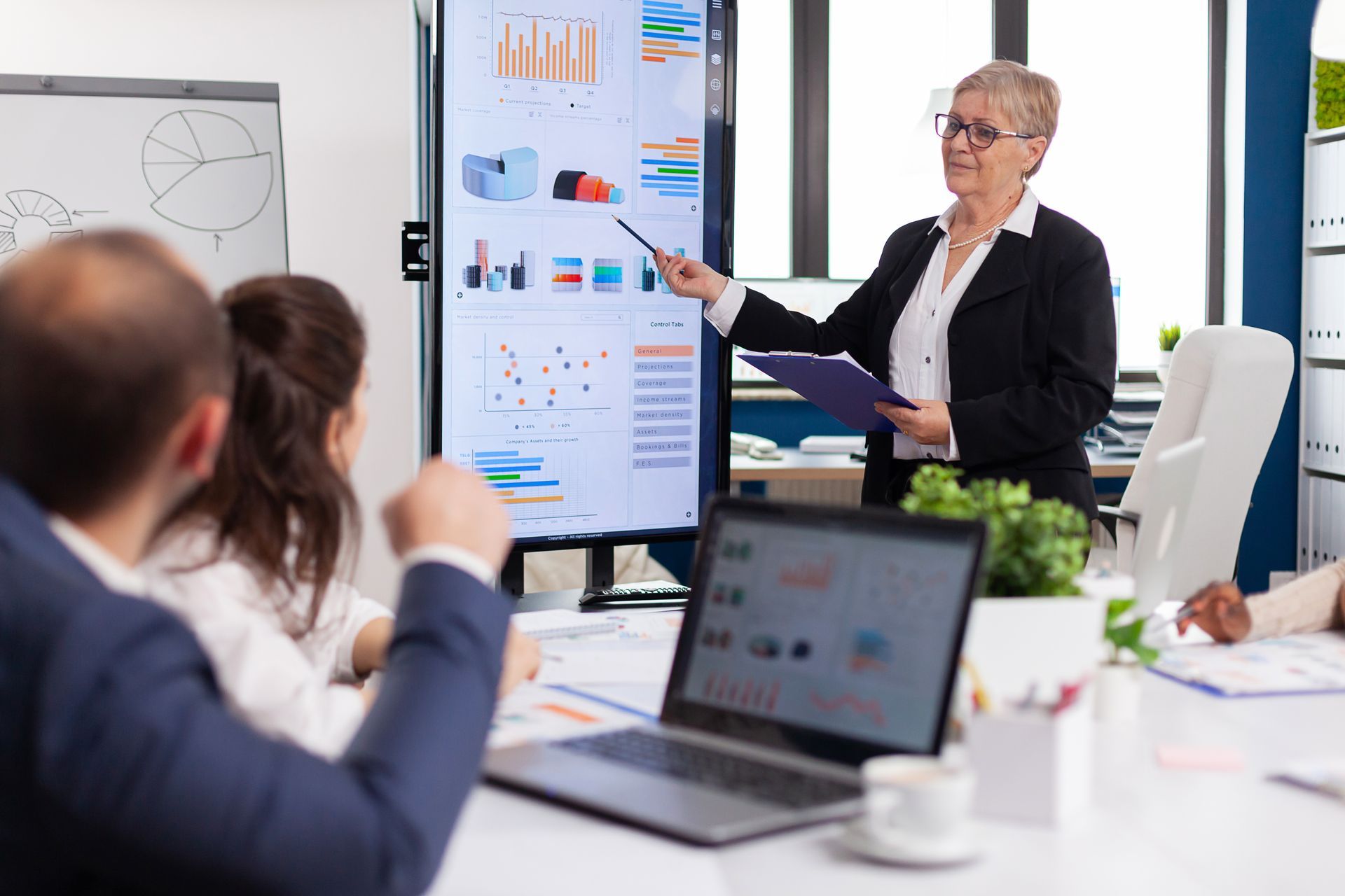 A woman is giving a presentation to a group of people in a conference room.