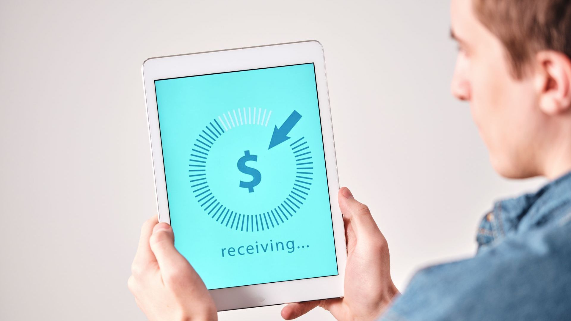 A man is holding a tablet with a dollar sign on it.