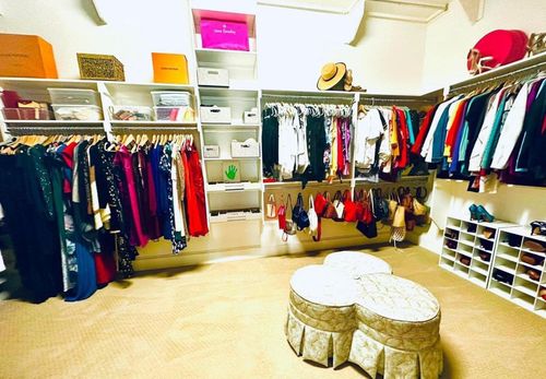 A large walk in closet filled with lots of clothes and shoes.