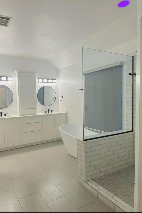A bathroom with two sinks , a tub , and a walk in shower.