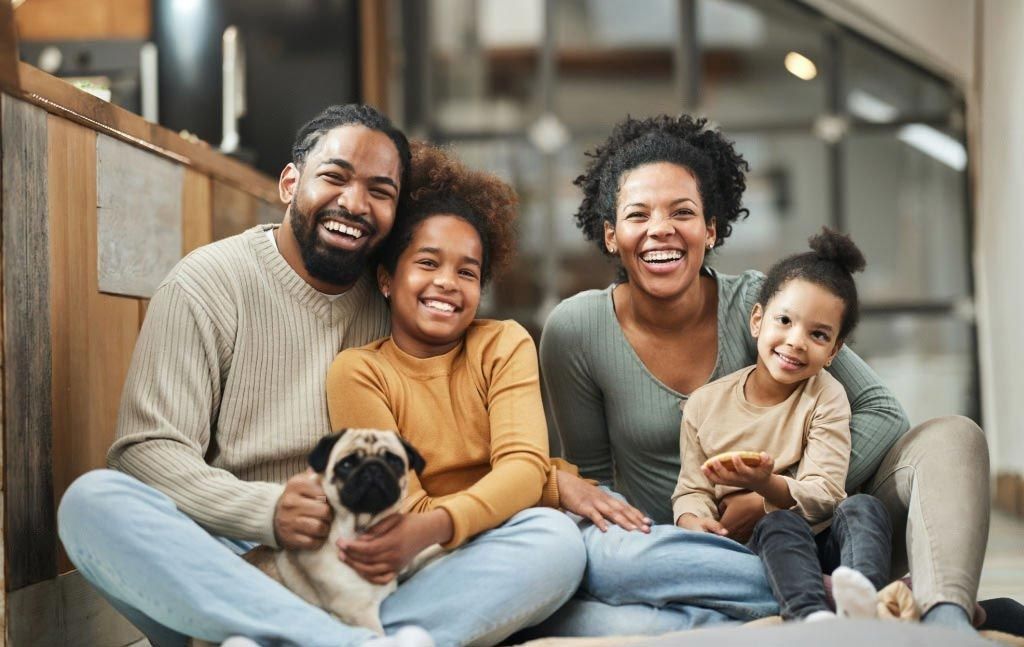 A family is sitting on the floor with a dog.