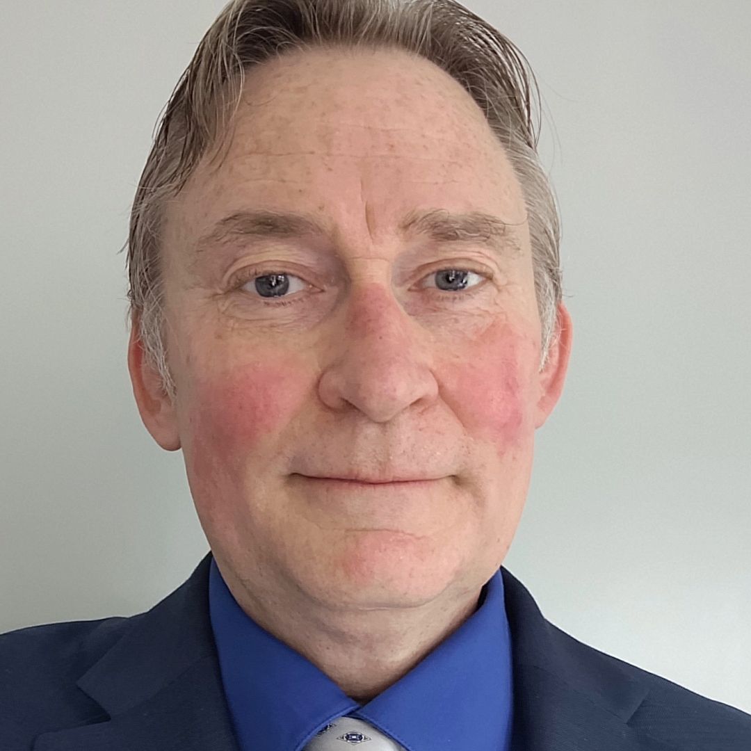 A man in a suit and tie is smiling for the camera.