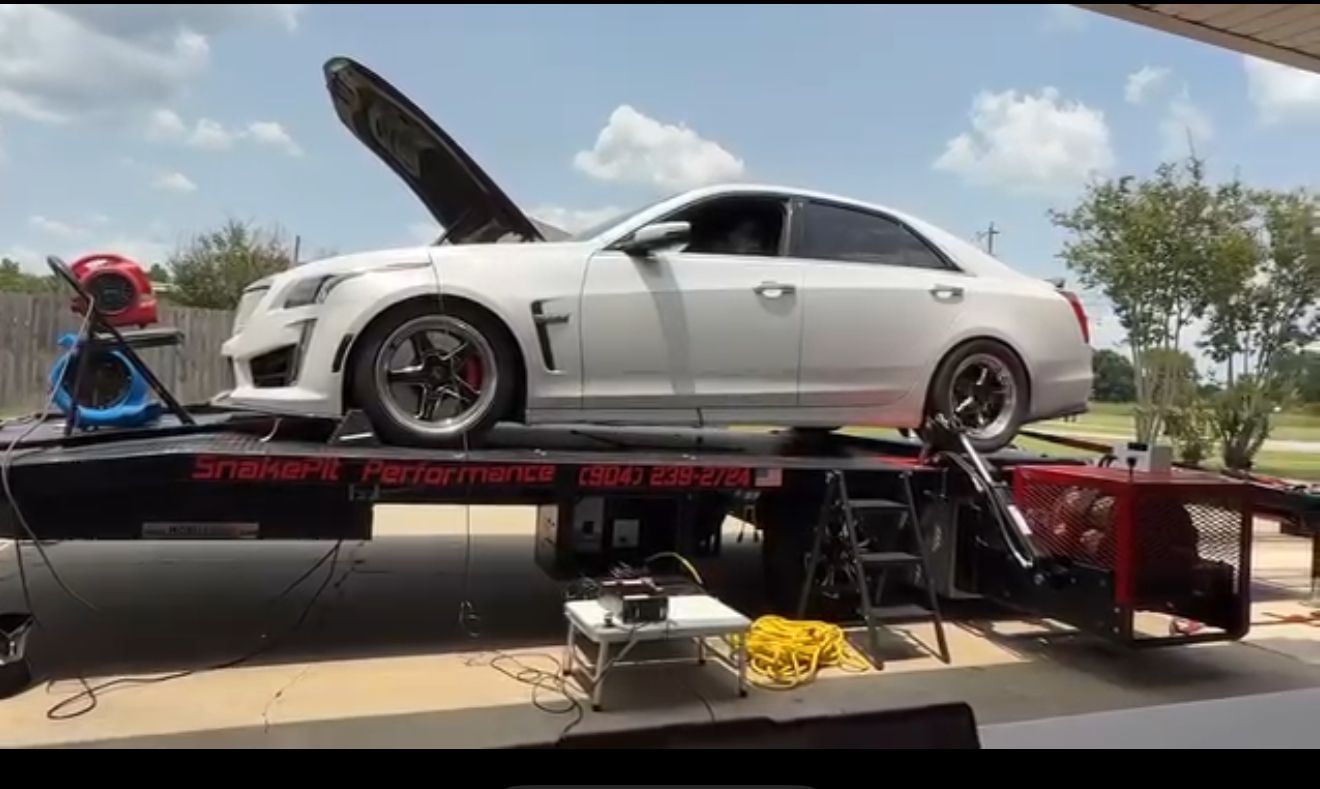 White Cadillac CTS-V on a dyno. Hood is up. Red brake calipers visible.